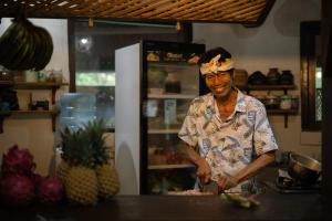 a woman standing in a kitchen preparing food at Meno Dream Resort in Gili Meno
