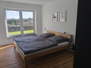 a bed in a room with two large windows at Alpenblick Living in Stetten +13 photos