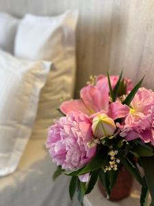 a bouquet of pink flowers sitting next to a bed at Hotel Provencal in Saint-Raphaël