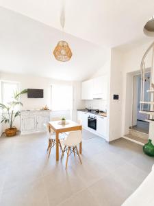 a white kitchen with a wooden table and chairs at Ca' Du Marchin, Noli. in Noli