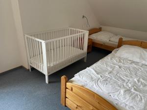two beds in a room with a crib at Ferienwohnungen Matschak OG rechts in Fehmarn