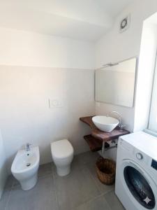 a bathroom with a toilet and a sink and a washing machine at Ca' Du Marchin, Noli. in Noli