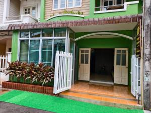 a green house with white doors and a porch at Happy Homey Hostel in Suratthani