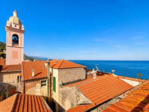 a view of roofs with a clock tower and the ocean at Ca' Du Marchin, Noli. in Noli +4 photos