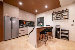 a kitchen with a bar with stools and a refrigerator at Morning Sea 1 เปิดใหม่!! พัทยาเหนือใกล้ทะเล ใกล้ Terminal21 in North Pattaya