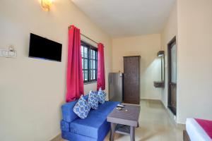 a living room with a blue couch and a tv at Hotel Salty Waves Baga in Baga