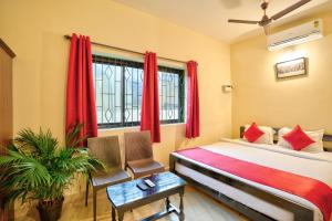a bedroom with a bed and a window with red curtains at Hotel Salty Waves Baga in Baga