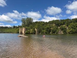 a person standing on a paddle board in a lake at La-Vialette Chambres d Hôtes in Mont-Roc +17 photos