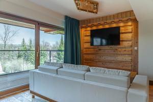 a living room with a couch and a flat screen tv at Mountain Diamond Resort in Zakopane