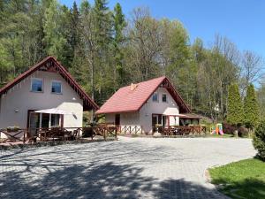 a white building with a red roof and picnic tables at Domki Pod Jesionami in Stronie Śląskie