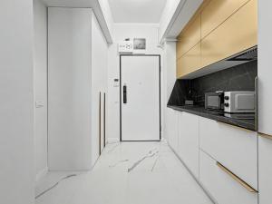 a white kitchen with a door and a microwave at Tomis Villa Grand Resort in Mamaia Sat/Năvodari