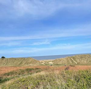 a grassy hill with the ocean in the background at Sandgate retreat hemsby 2023 in Hemsby