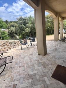 a patio with chairs and a table and a stone wall at Studio pied de coline LYVIN in Ginasservis