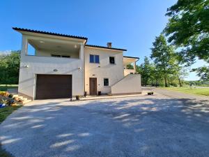 a large white house with a large garage at Apartman Tea in Pićan