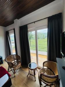 a living room with chairs and a large window at Pine Trees Home Holidays in Vagamon
