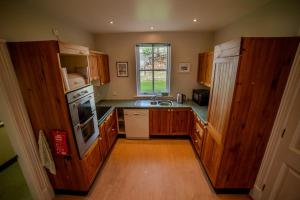 a kitchen with wooden cabinets and a sink and a window at Crossing Gates House in Dundrum