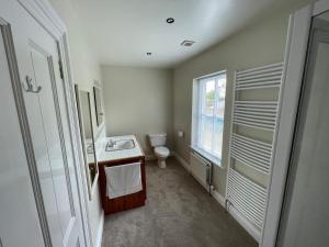 a bathroom with a toilet and a sink and a window at Crossing Gates House in Dundrum +23 photos