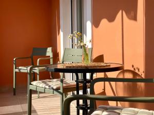 a table with chairs and a vase with flowers on it at Delta Apartment • next to the beach in Roda