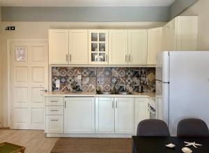 a kitchen with white cabinets and a white refrigerator at Delta Apartment • next to the beach in Roda