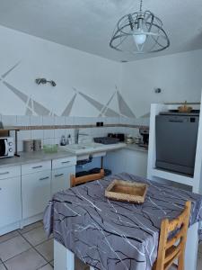 a white kitchen with a table and a tv at La Grande Ferme in Arinthod +4 photos