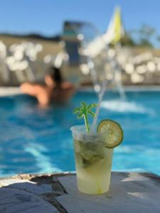 a drink with a lime on a table next to a swimming pool at Pousada Caminho das Aguas in Lindóia
