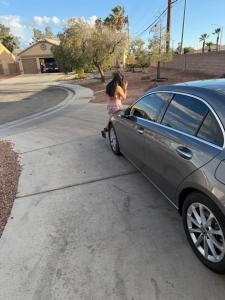 a little girl is sitting next to a car at EdCccc life in Las Vegas