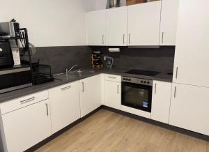 a kitchen with white cabinets and a stove top oven at Home Away From Home in Schönefeld +8 photos