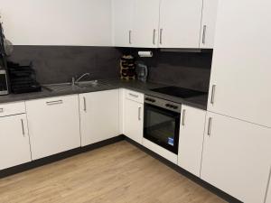 a white kitchen with white cabinets and a sink at Home Away From Home in Schönefeld