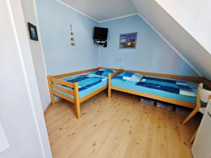 two beds in a room with blue walls and wooden floors at Schulstrasse 10a Fewo in Zingst