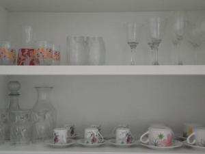 a shelf filled with glasses and cups and vases at Dna Smart Style in Goiânia