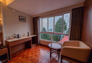 a hotel room with a desk and a large window at Hotel Old Bellevue Heritage Stay with Mountain Views in Chowrasta Darjeeling in Darjeeling