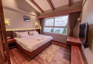a bedroom with a bed and a tv and a window at Hotel Old Bellevue Heritage Stay with Mountain Views in Chowrasta Darjeeling in Darjeeling