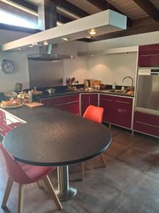 a kitchen with a black table and red chairs at Maison zen in Laval-Pradel