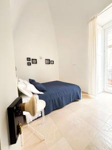 a white bedroom with a bed and a chair at Dimora Veneziani in Bisceglie
