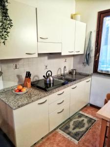 a kitchen with white cabinets and a bowl of fruit on the counter at Casa Oscar in Catabbio
