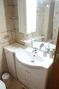 ein Badezimmer mit einem weißen Waschbecken und einem Spiegel in der Unterkunft Ouranos Apartment in Athen