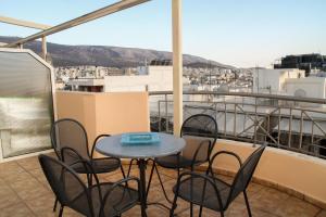 einen Tisch und Stühle auf einem Balkon mit Aussicht in der Unterkunft Ouranos Apartment in Athen