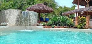 a swimming pool with a waterfall and an umbrella at Ecolodge Nosy Faly in Nosy Be