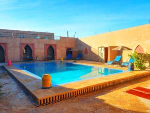 a large swimming pool in a courtyard with a building at La Source Desert Camp in Adrouine