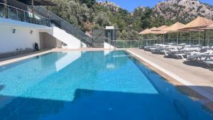 a large blue swimming pool with chairs and umbrellas at Mavinin ve Yeşilin dansı, Panoramik manzara, 75m2 in Marmaris