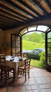 a dining room table with chairs and a view of a car at Maison Le Grand Saule in Bugnein
