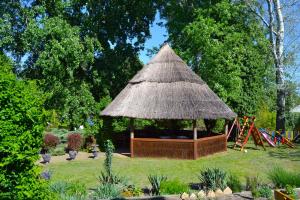 a gazebo with a straw roof in a garden at Čarda Ranč in Berava