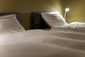 a close up of a bed with white sheets and pillows at Desroches House in Kanazawa