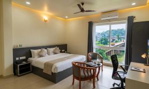 a bedroom with a bed and a desk and a window at RIVULET River Side Budget Business Class Hotel in Mukkam