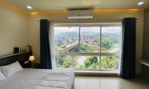 a bedroom with a large window with a view at RIVULET River Side Budget Business Class Hotel in Mukkam