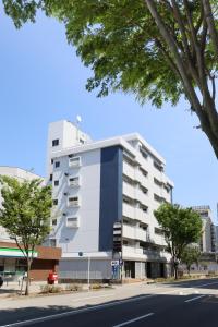 a tall white building on a city street at Desroches House in Kanazawa
