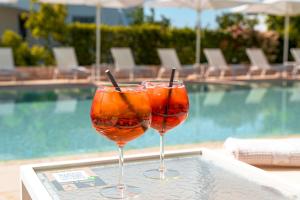 two wine glasses sitting on a table next to a swimming pool at Borgo Cozzana in Monopoli