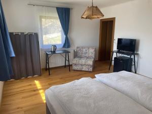 a bedroom with a bed and a chair and a television at Pension Victoria in Millstatt