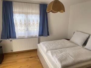 a bedroom with a bed and a window with blue curtains at Pension Victoria in Millstatt