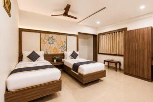 a bedroom with two beds and a ceiling fan at Hotel Comfort Park - Opposite Sri Ramachandra Medical College Porur in Chennai